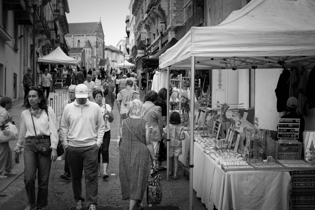 Un puesto de bisutería en el mercado y transeúntes andado por la calle, fotografía en blanco y negro