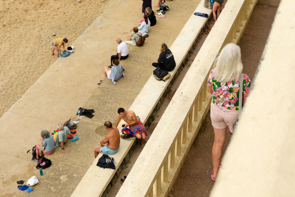 Unas personas sentadas en la playa de Biarritz en diferentes niveles