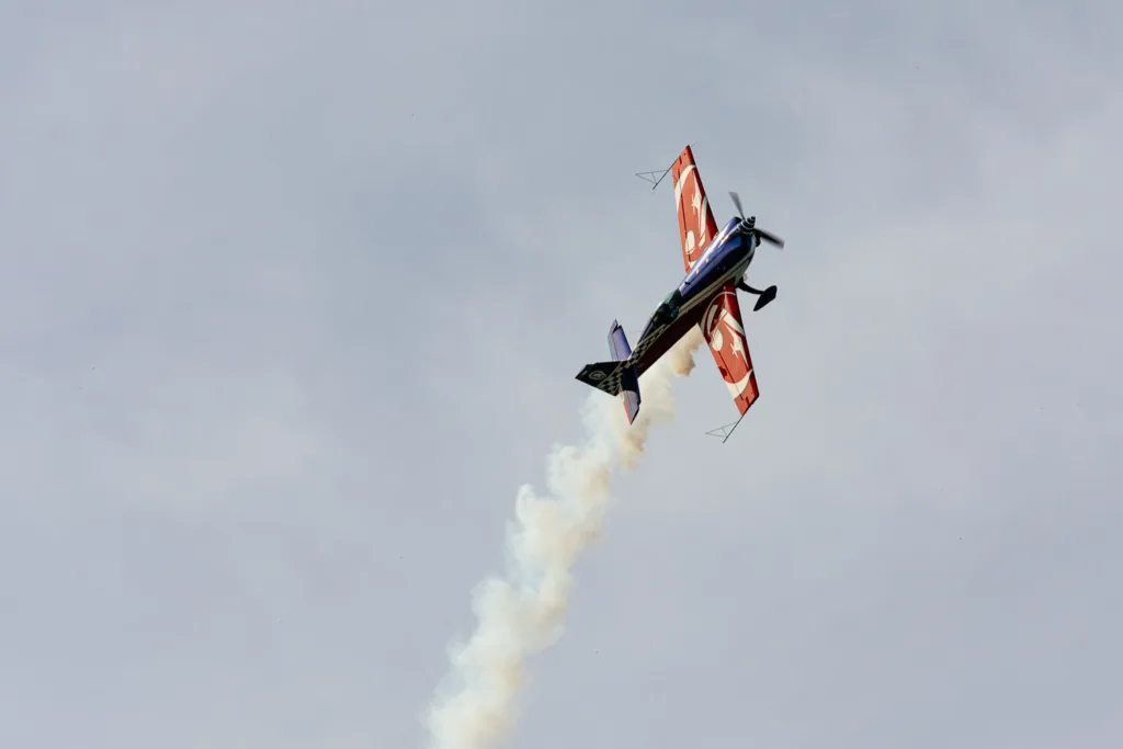 Avión de acrobacias azul y rojo con estela de humo blanco