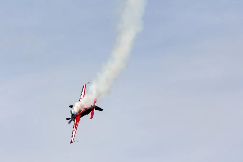 Avión de acrobacias azul y rojo con estela de humo blanco